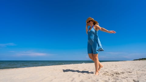 Woman walking on sandy beach in summer dress