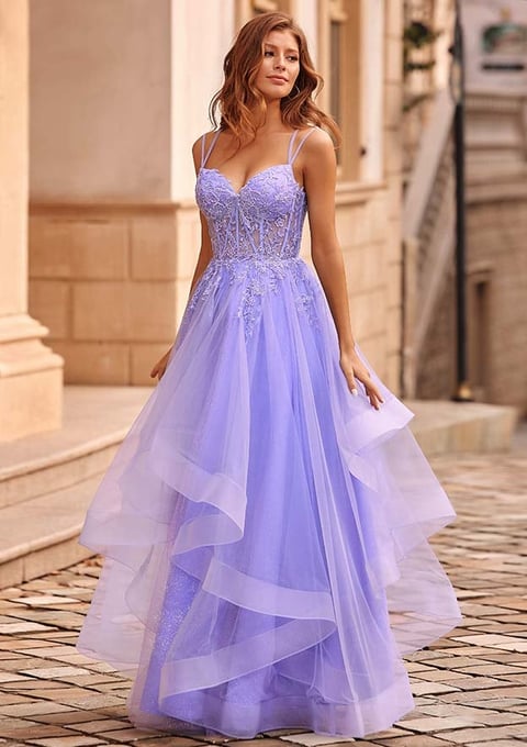 Woman wearing a lavender tulle gown with beaded bodice and flowing skirt standing in an elegant hallway