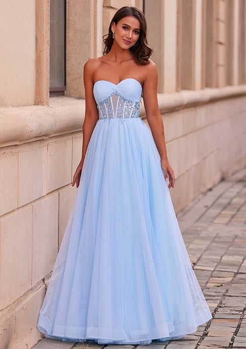 Woman in light blue strapless sweetheart neckline gown with corset bodice and flowing tulle skirt standing in an elegant architectural corridor