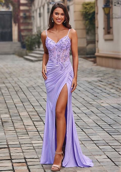 Woman in lavender sequin evening gown with high slit standing on a brick courtyard